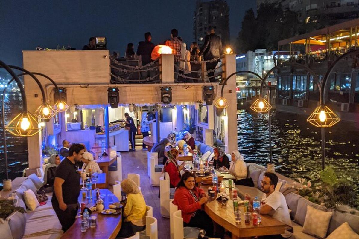 a group of people sitting at tables in a restaurant by the water