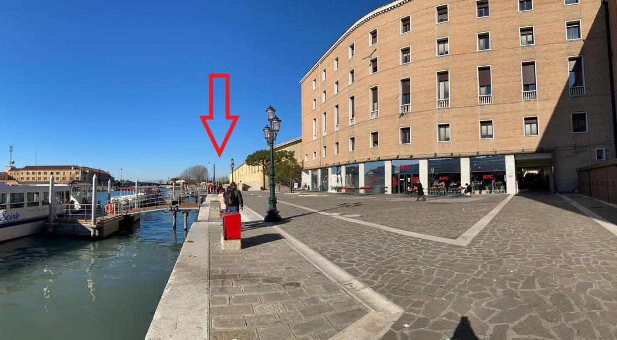 una fletxa vermella que apunta a un edifici al costat d'un riu