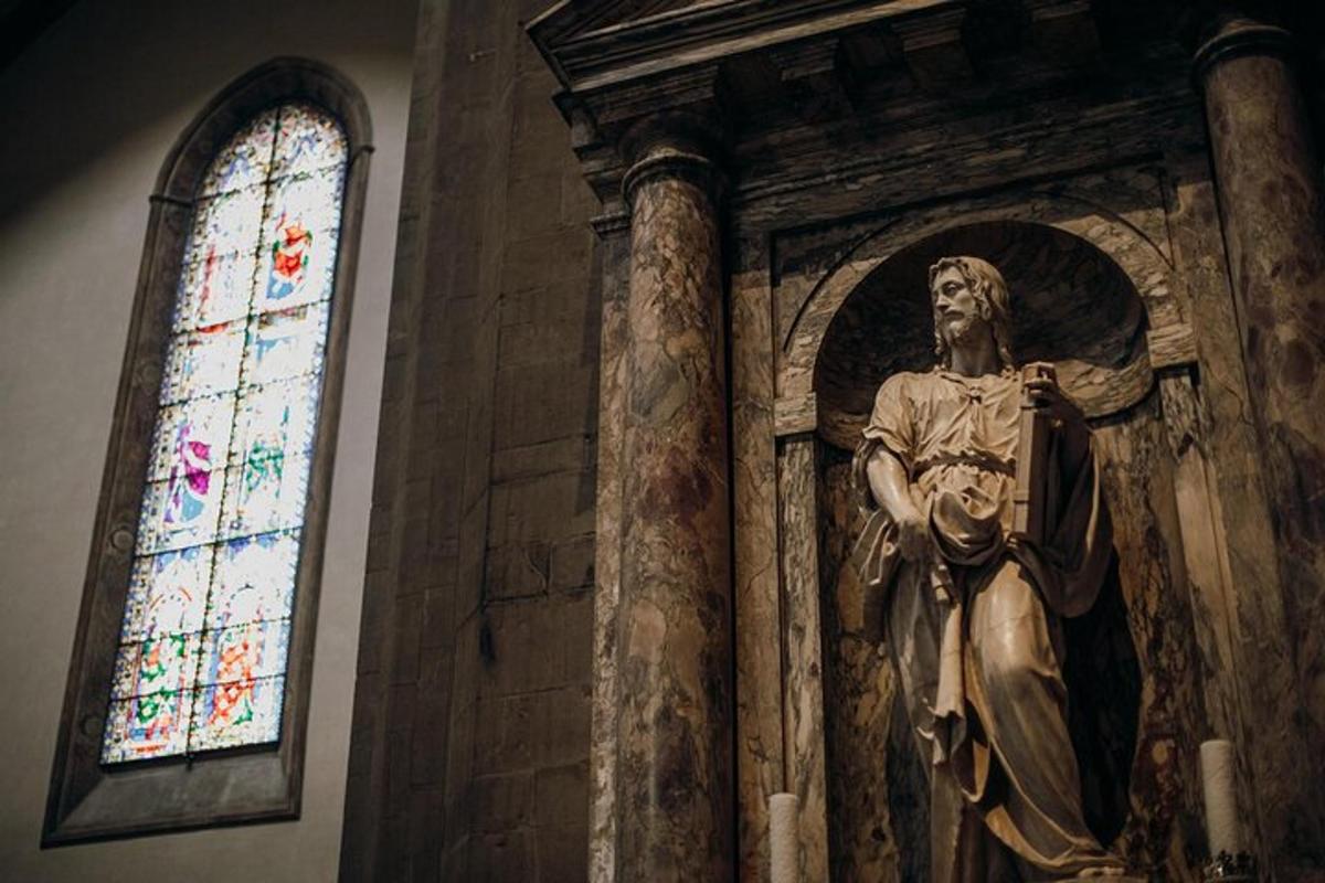 een beeld van een heilige in een kerk met een glas-in-loodraam