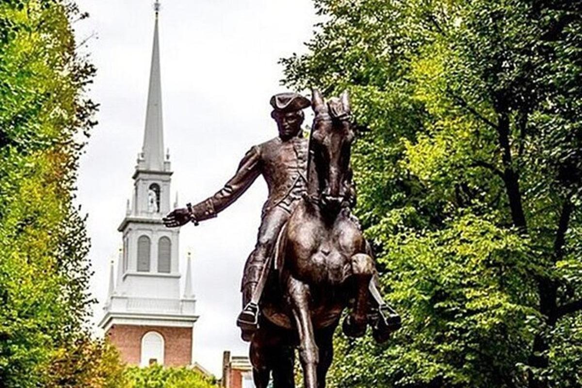 en statue av en mann som rir på en hest foran en kirke