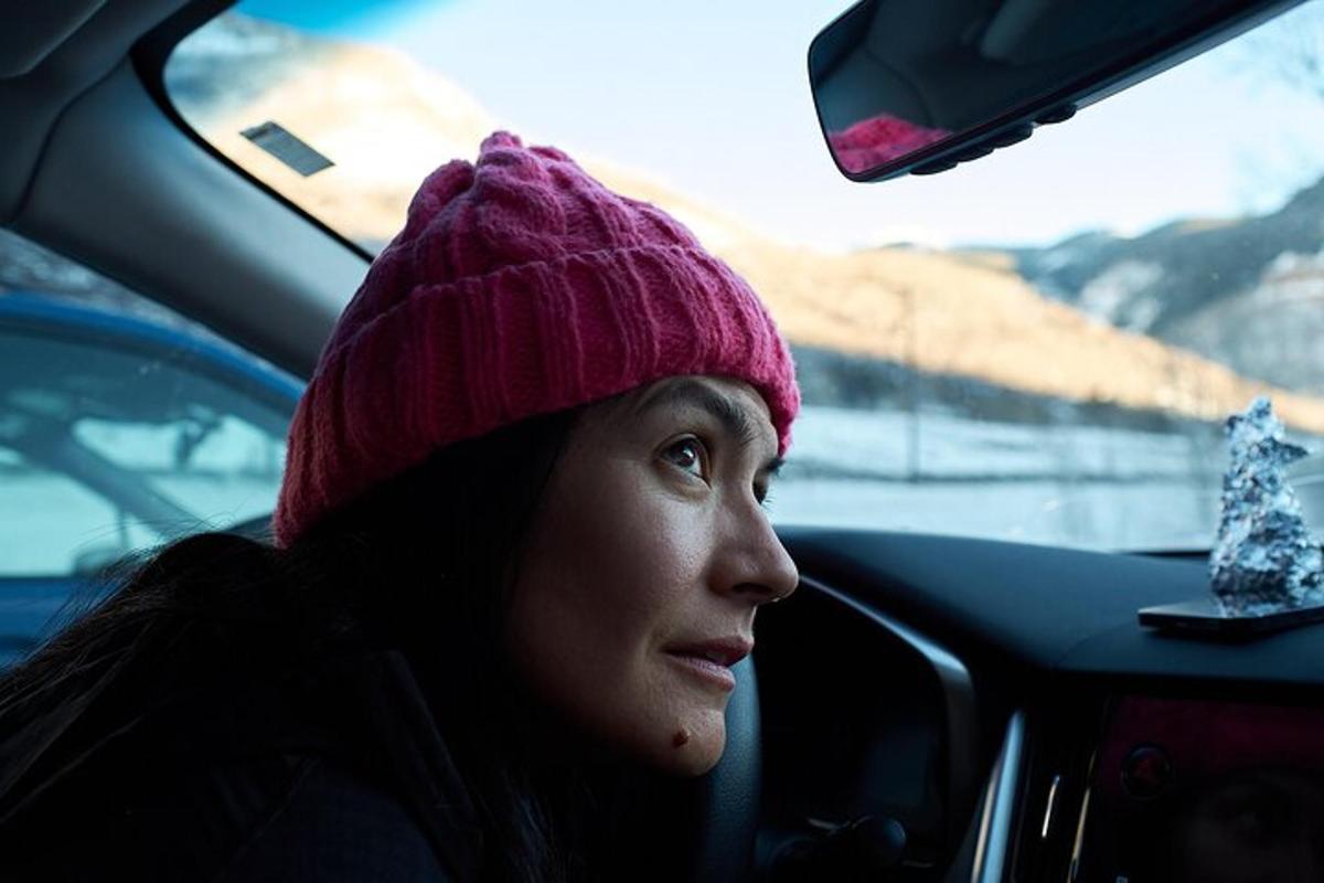 a woman sitting in a car wearing a pink hat