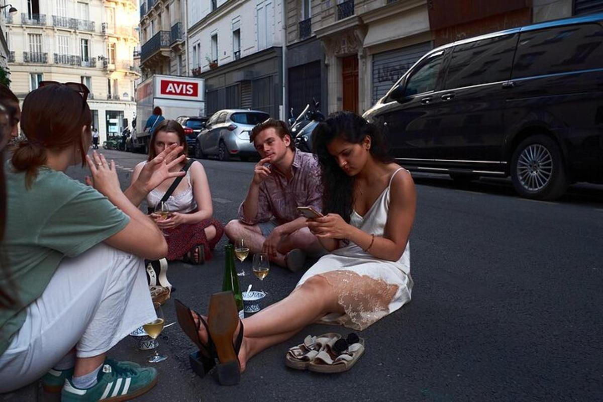 a group of people sitting on the street looking at their cell phones