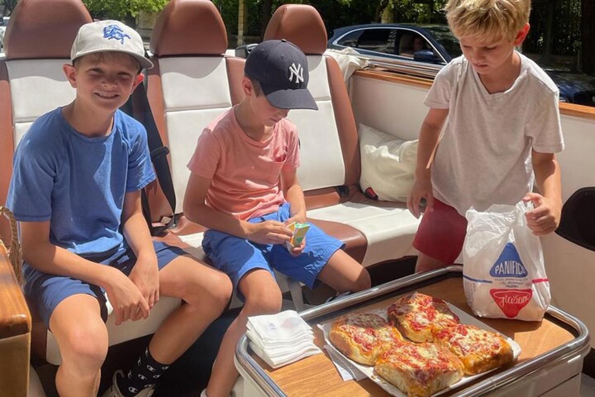 tři chlapci sedící v zadní části auta s pizzou