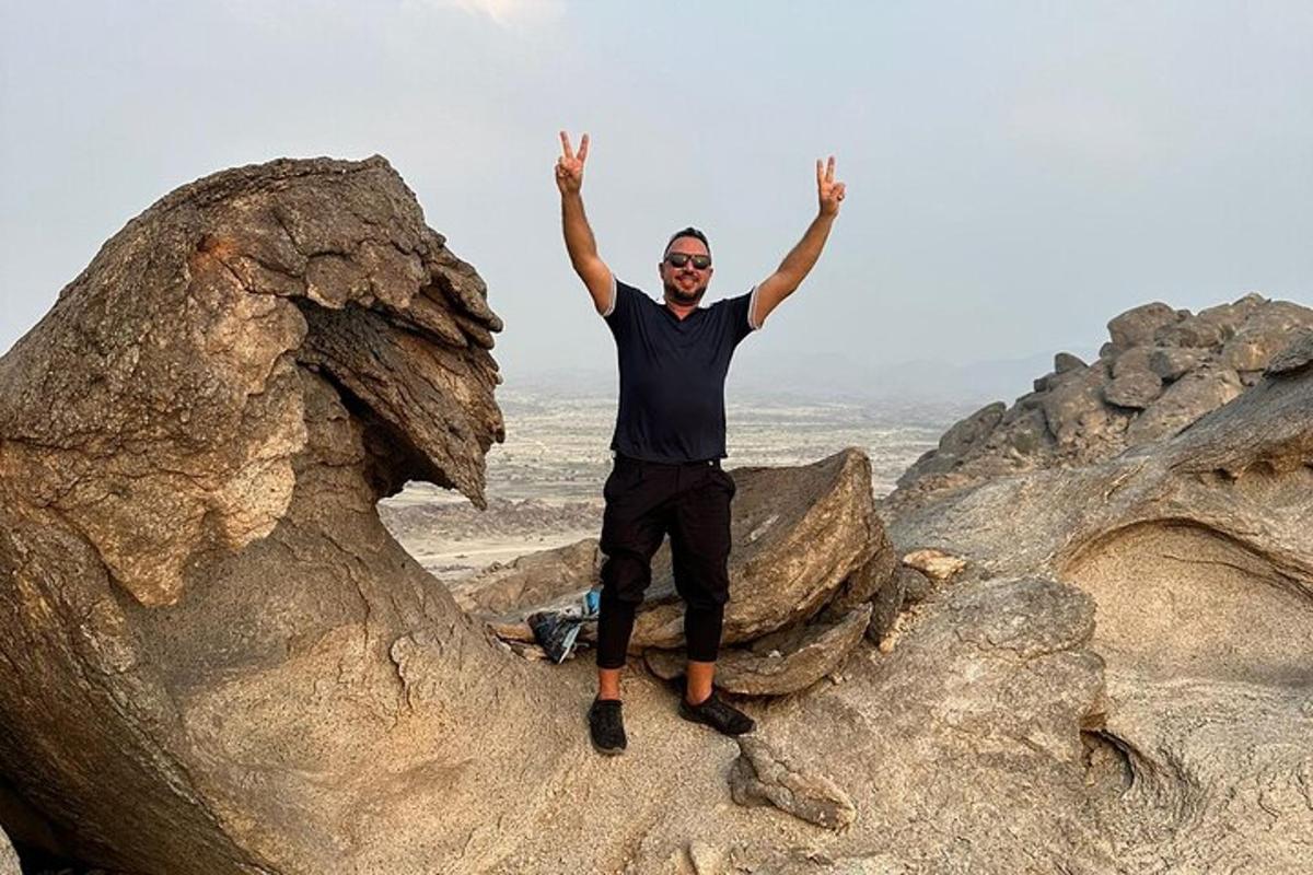 a man standing on some rocks with his hands in the air