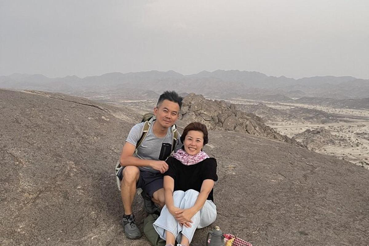 two people sitting on the top of a mountain