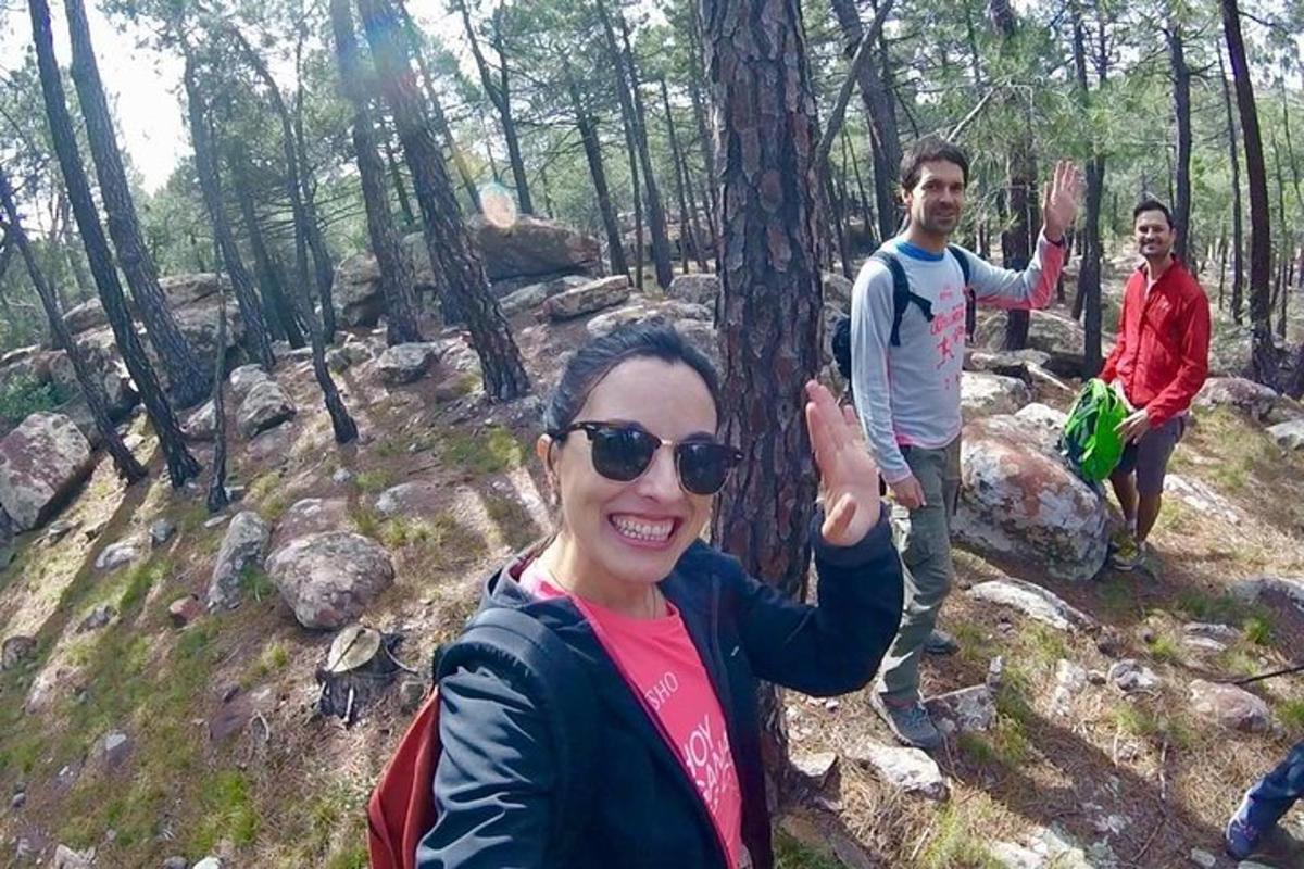 a woman standing in the woods with her hand up