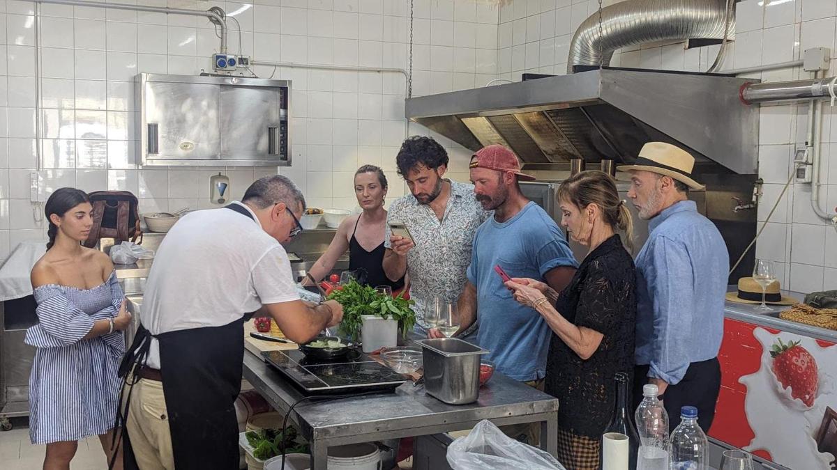 um grupo de pessoas em pé em uma cozinha preparando comida
