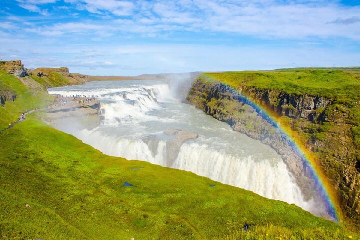 uma cachoeira com um arco-íris ao lado