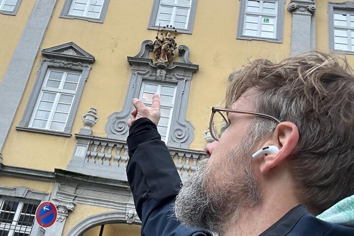 muž stojící před budovou s rukou ve vzduchu