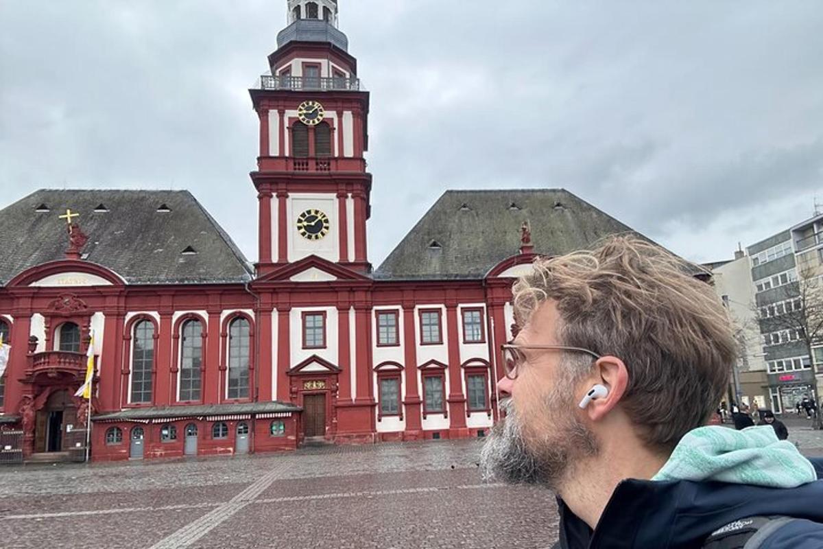 en mann som står foran en stor bygning med et klokketårn