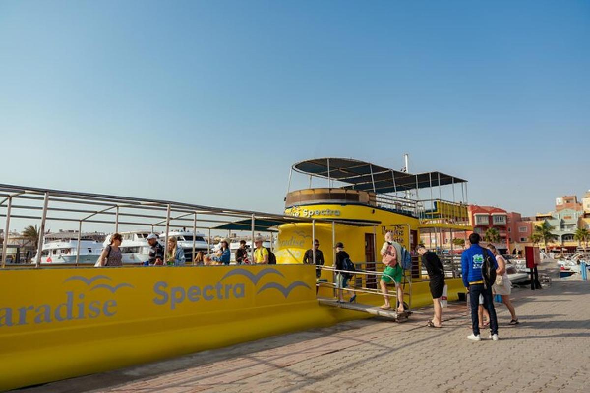 Un barco amarillo en un muelle con gente en él.