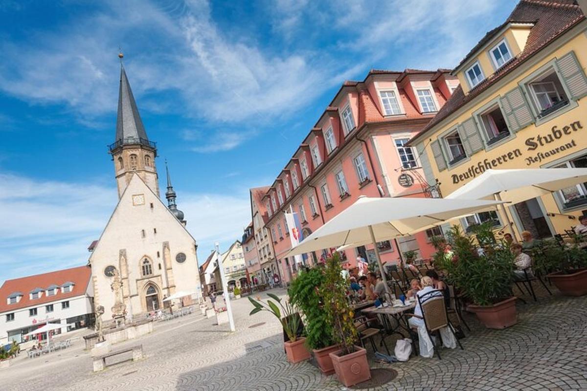 a group of people sitting at tables on a street with a church