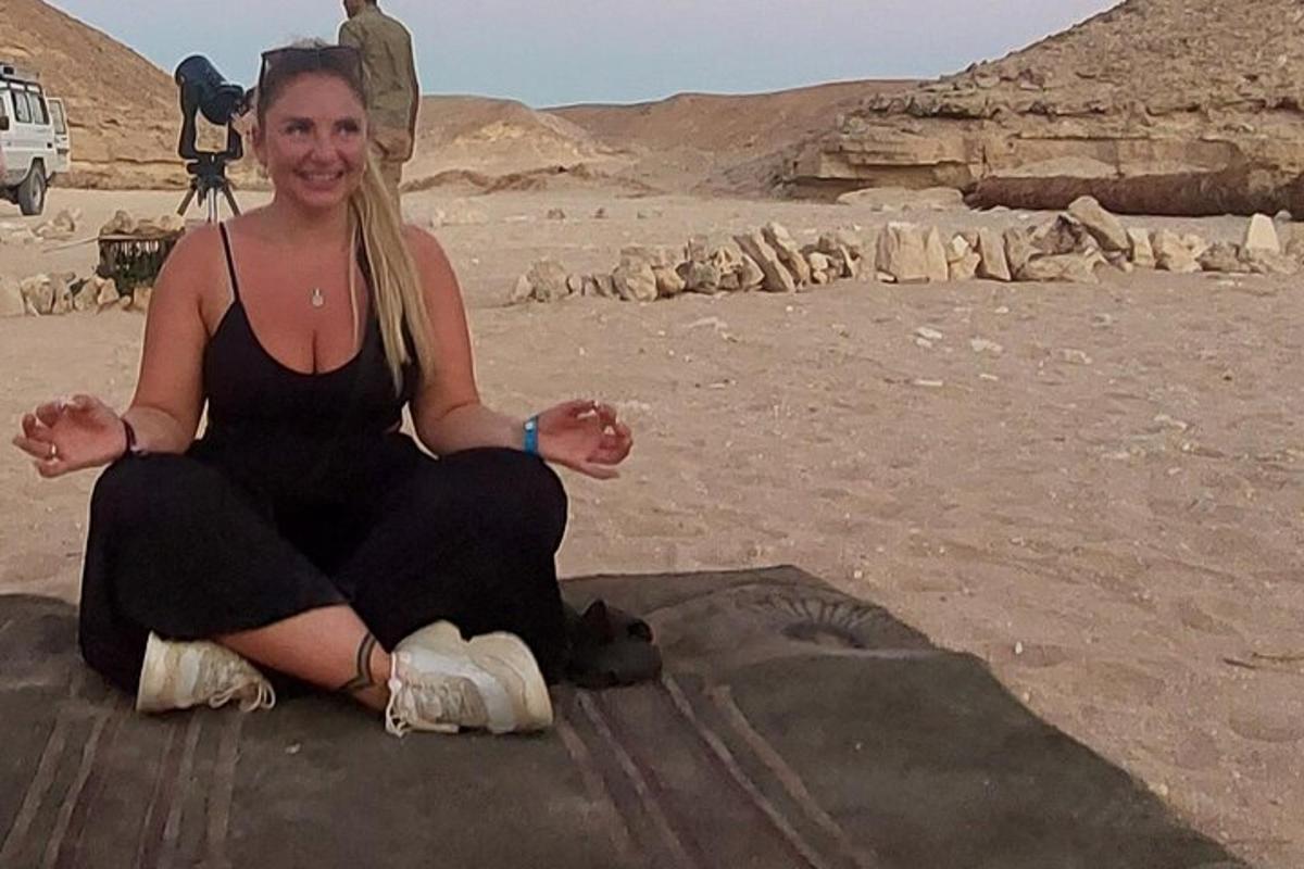 una donna seduta a terra nel deserto
