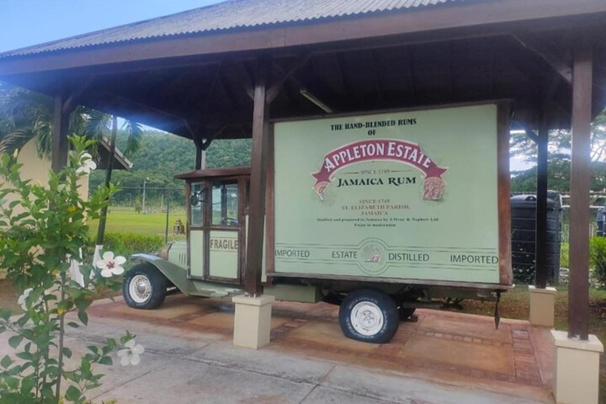a green truck parked under a building with a sign