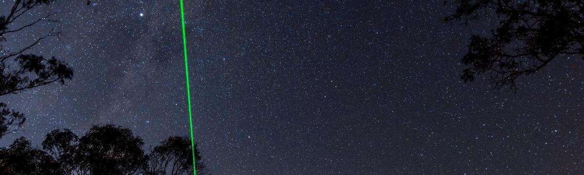 a green line in the night sky with trees