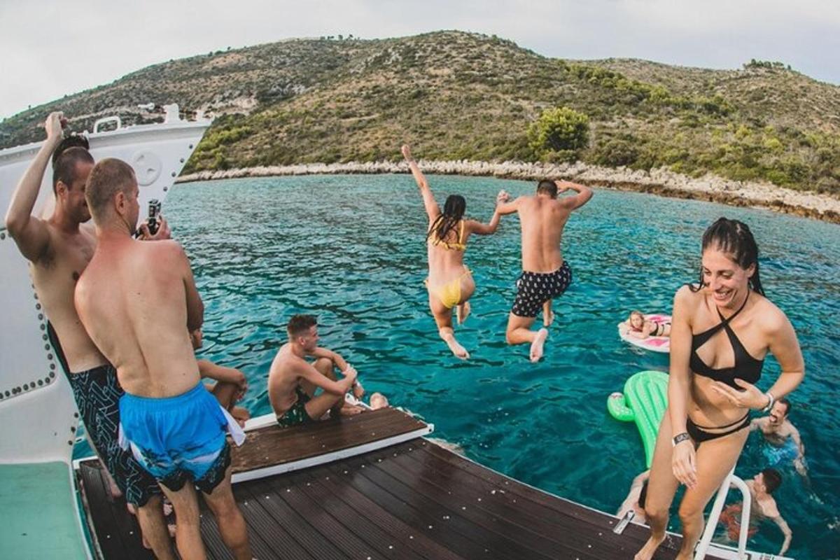 a group of people jumping into the water on a boat