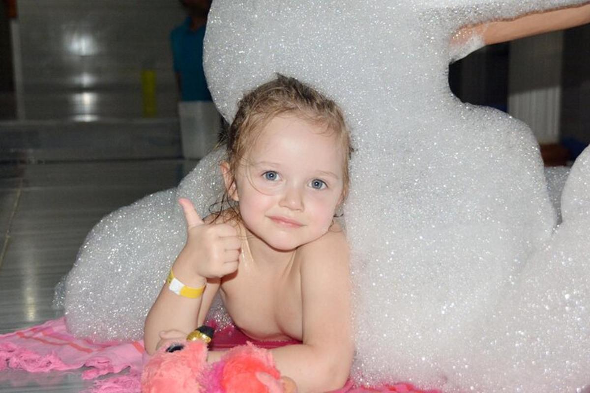 un bambino seduto nella vasca da bagno che fa un gesto di pollice in su