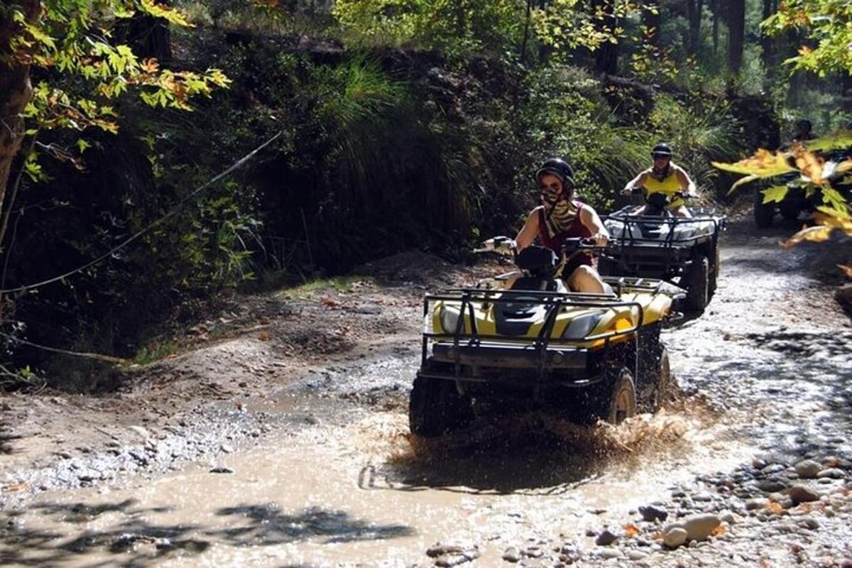 due persone che guidano un quad su una strada sterrata