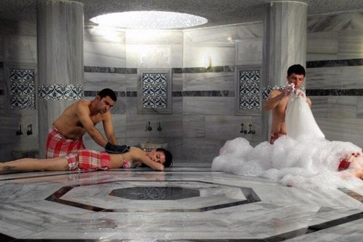 a group of three men in a bathroom with a bubble bath