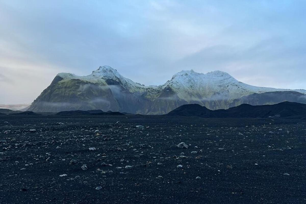 ein Berg mitten auf einem Feld mit Bergen im Hintergrund
