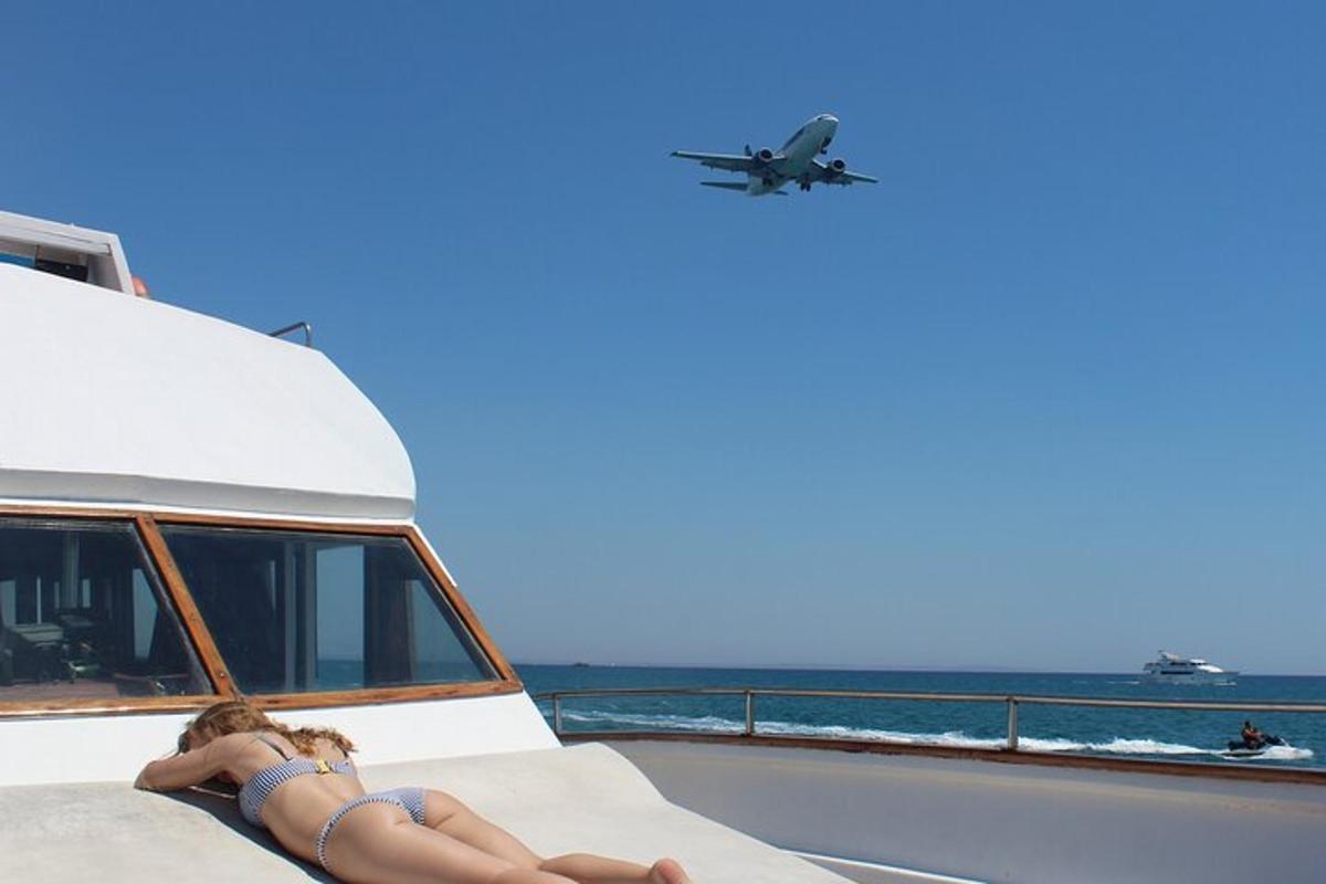 una persona sdraiata su una barca con un aereo nel cielo