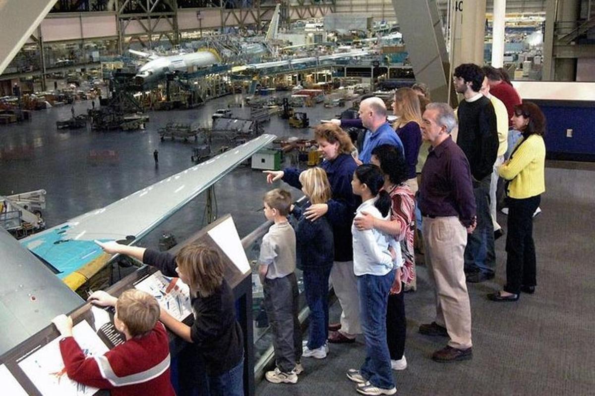 a group of people standing in a factory looking at an airplane