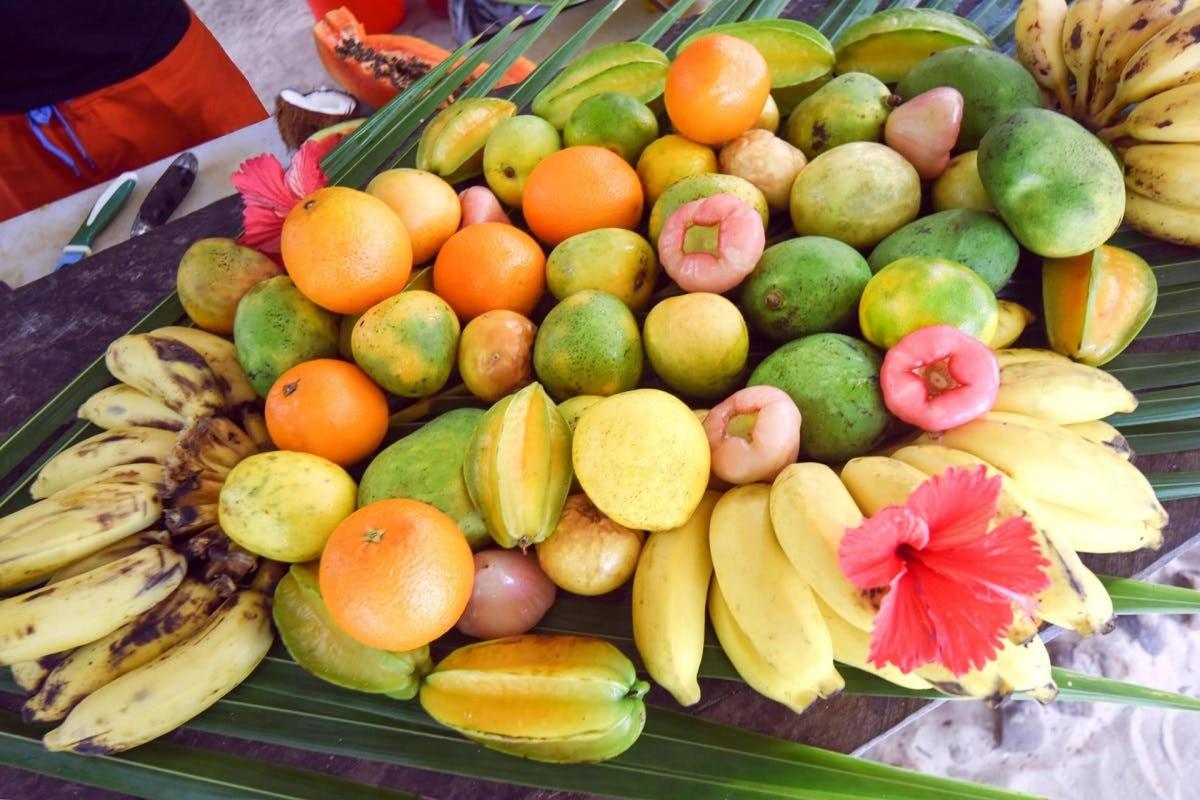 a pile of fruit on a table with bananas and oranges