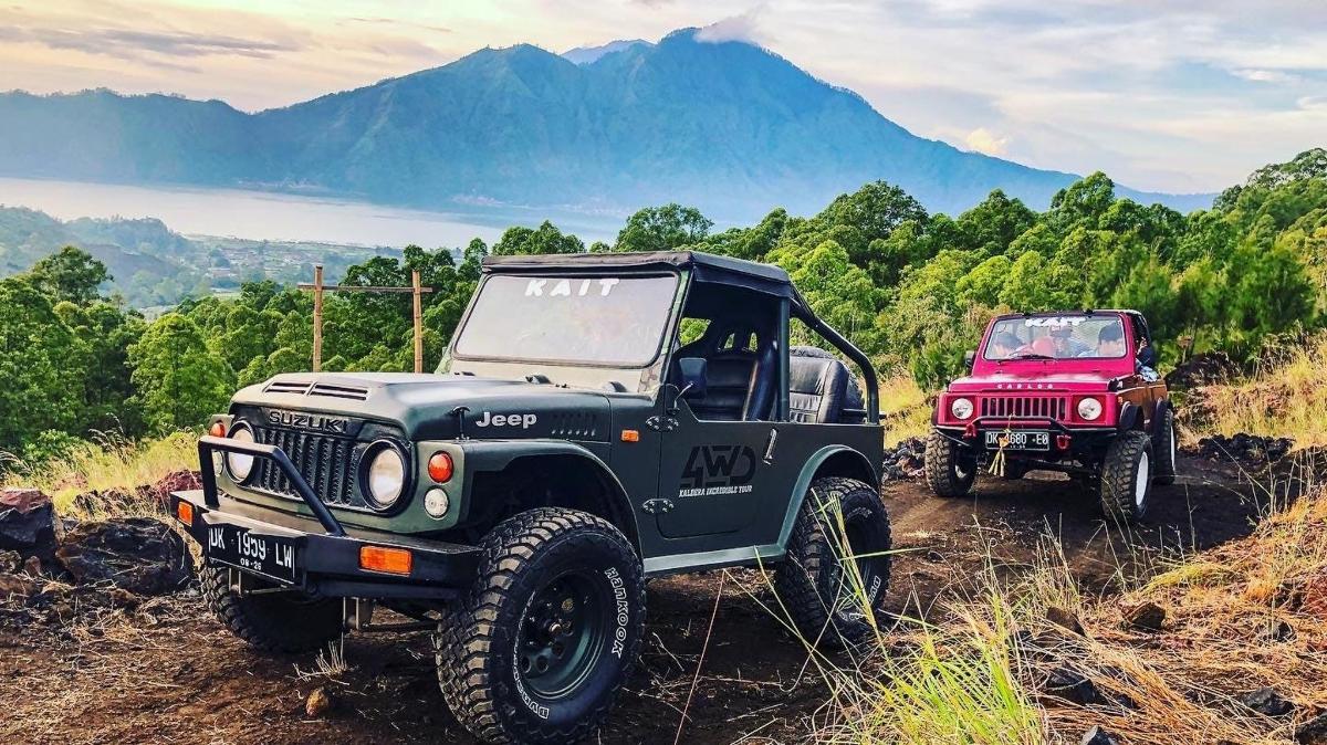 two jeepneys parked on a dirt hill with mountains in the background
