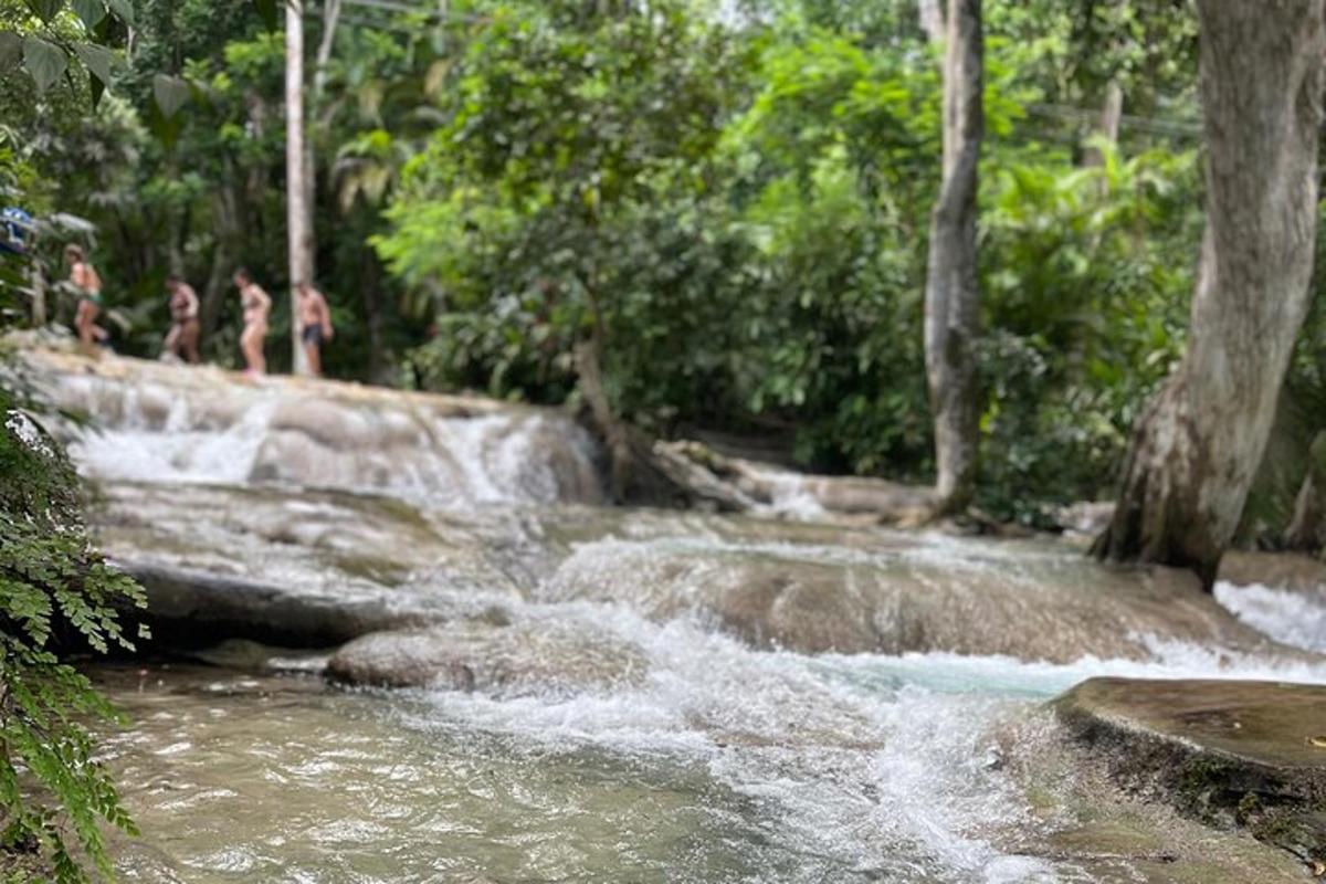 um grupo de pessoas em pé em frente a uma cachoeira