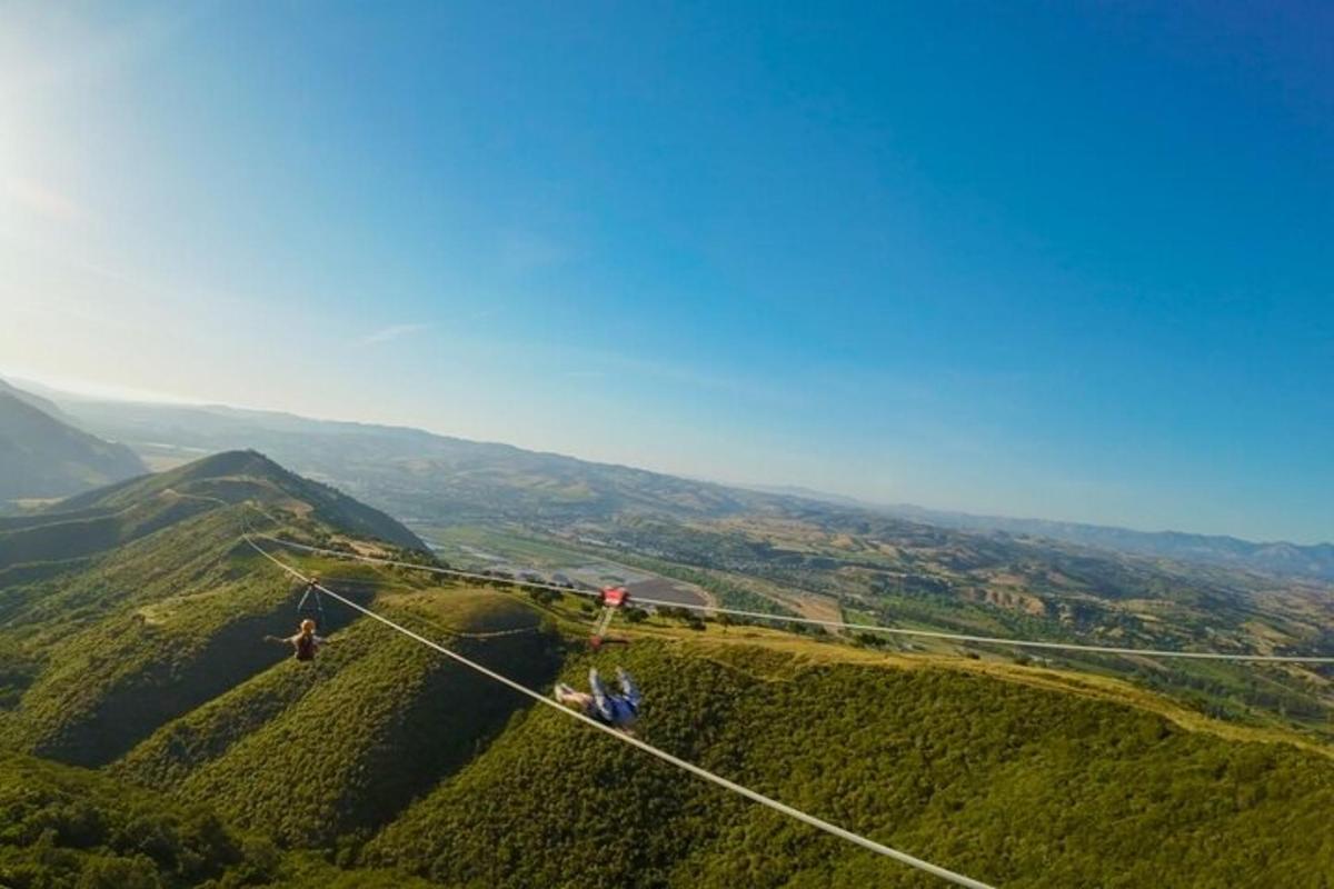 two people on a zip line over a mountain
