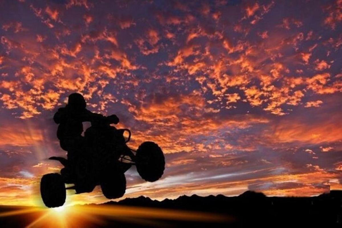 una persona conduciendo una motocicleta todoterreno al atardecer
