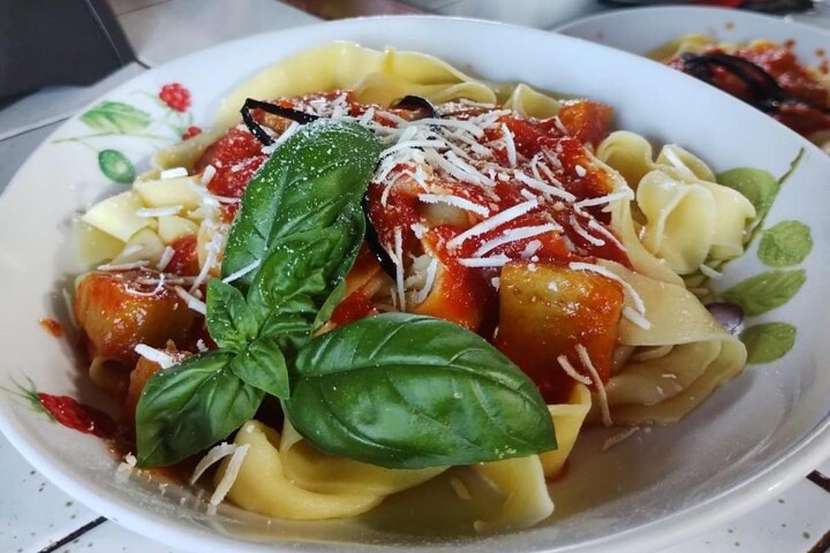 a white bowl of pasta with basil on top