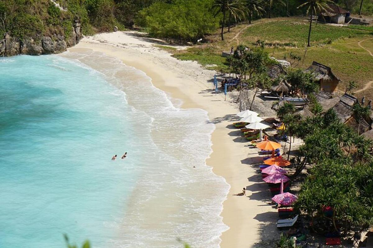 Una playa con sombrillas y gente nadando en el agua.