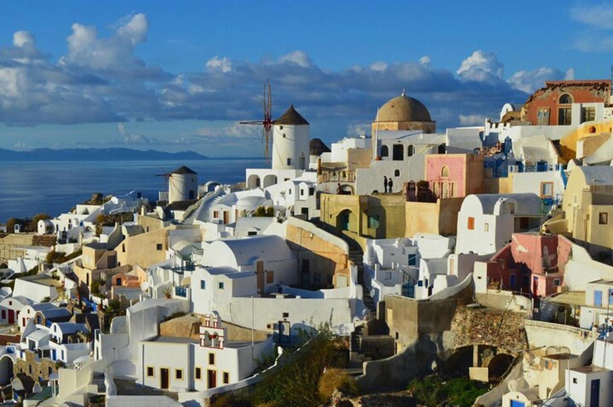 a group of white buildings on a hill with the ocean