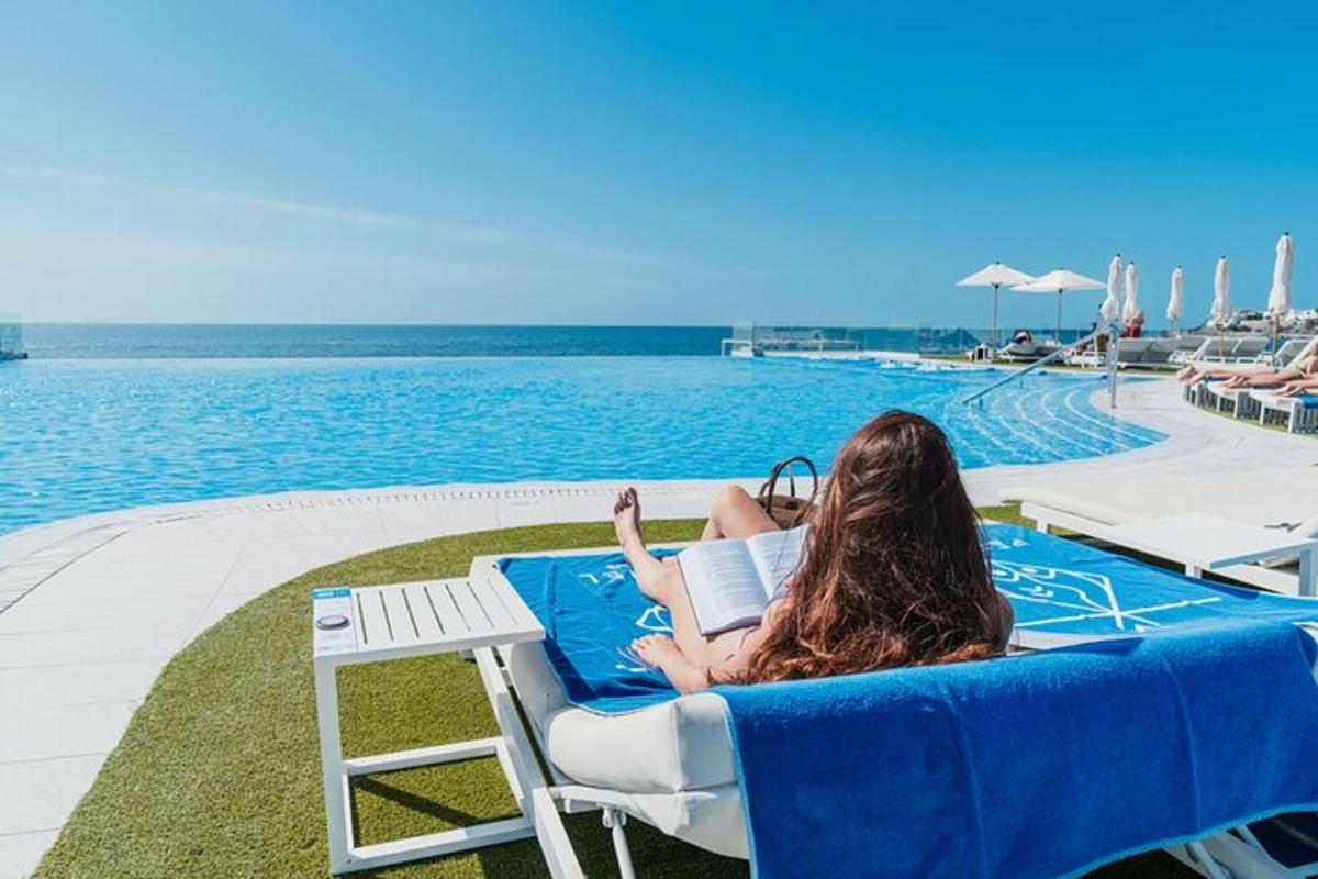 a woman laying in a chair reading a book by a pool