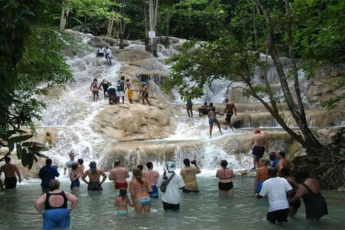 a group of people in the water at a waterfall