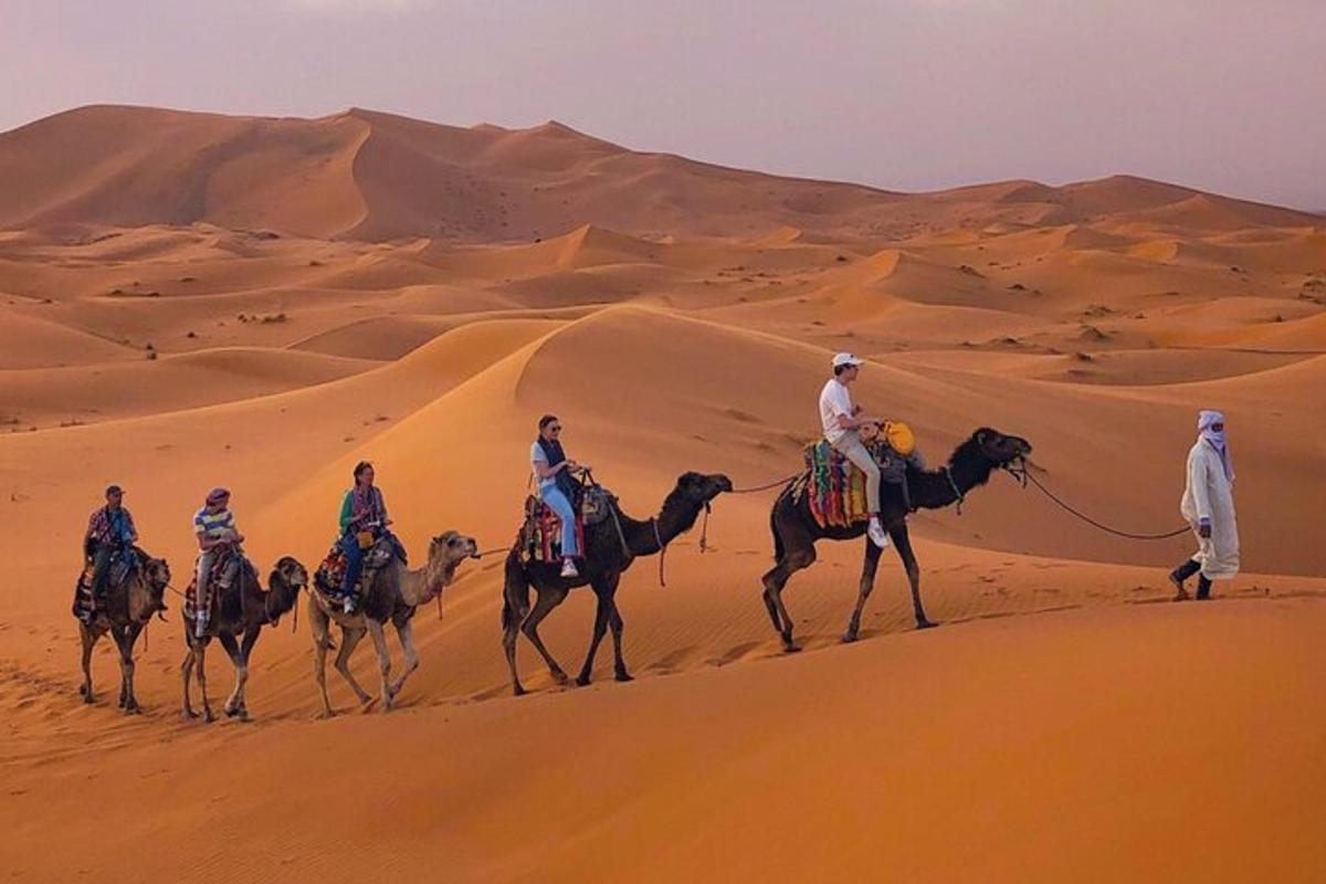 Un grupo de personas montando camellos en el desierto.