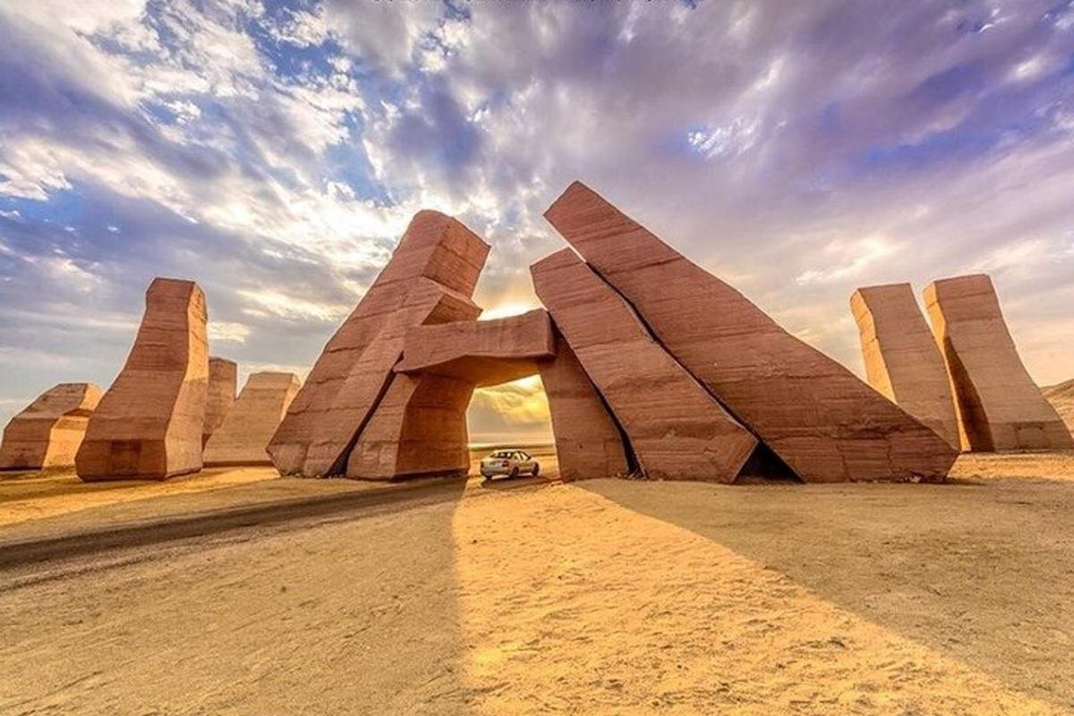 Un coche está aparcado delante de una escultura en el desierto.