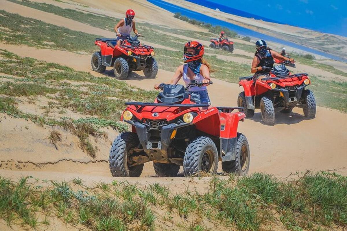 Grupa ludzi jeżdżących na quadach po plaży