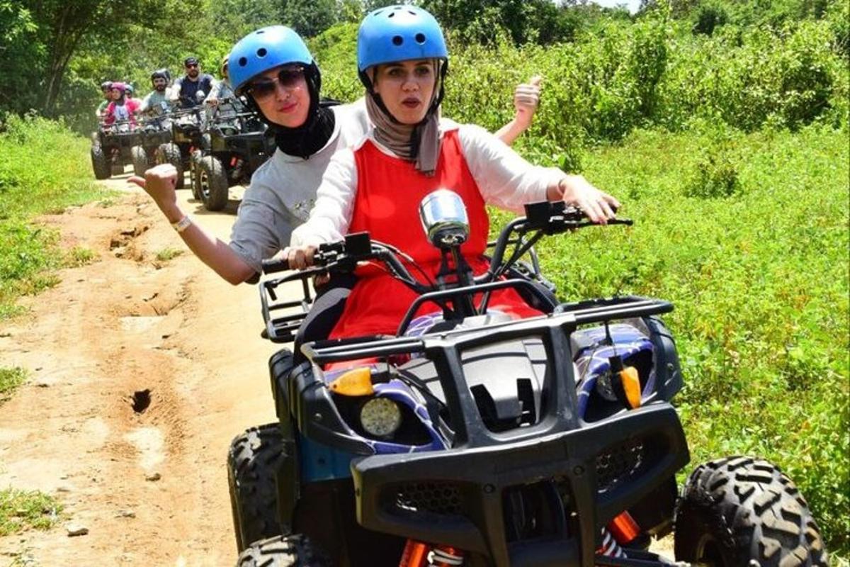 two people riding on a four wheeler on a dirt trail
