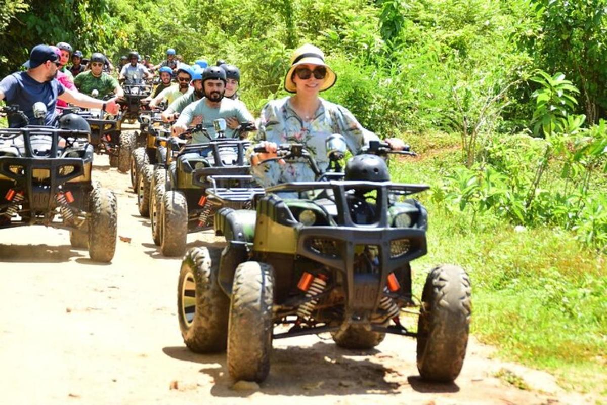 Un grupo de personas conduciendo vehículos todo terreno por un camino de tierra.