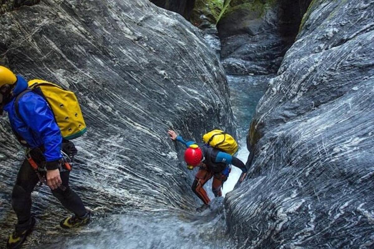 two people with backpacks climbing on a waterfall