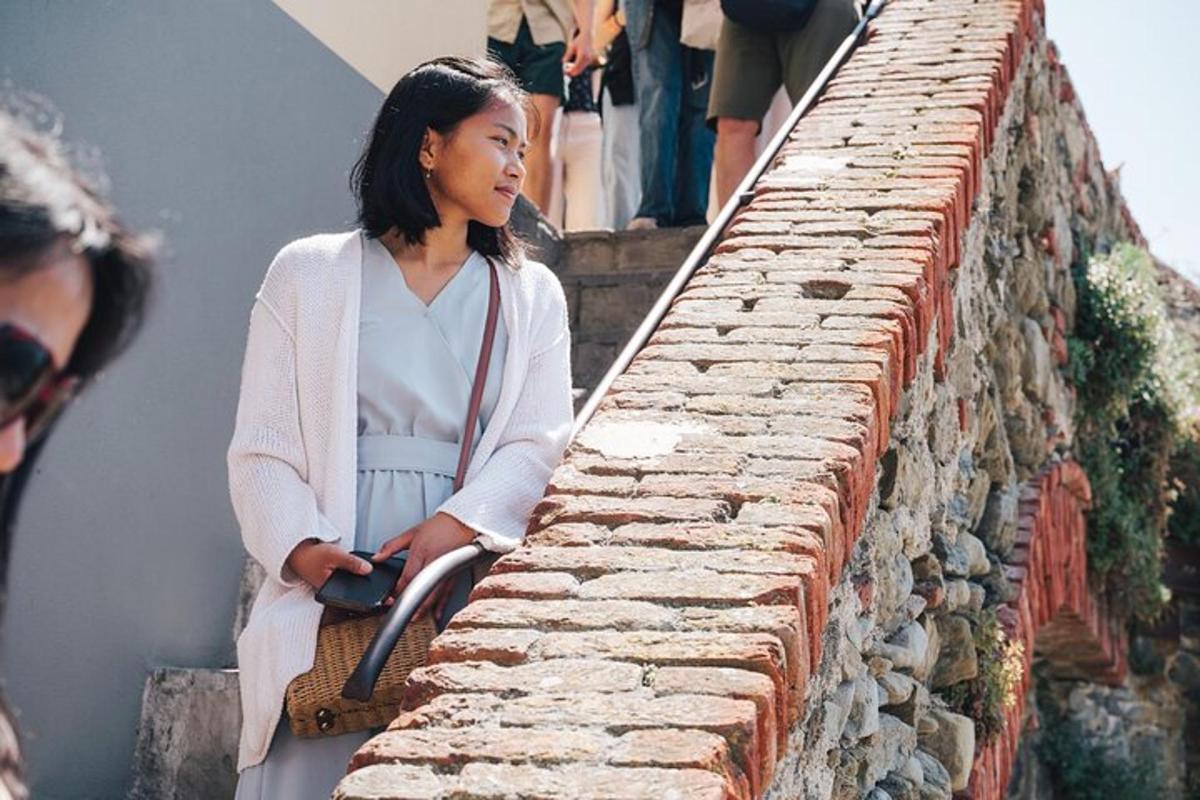 一位女士站在砖墙旁边