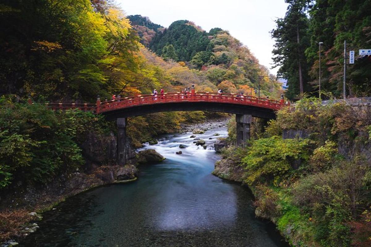 a group of people crossing a red bridge over a river
