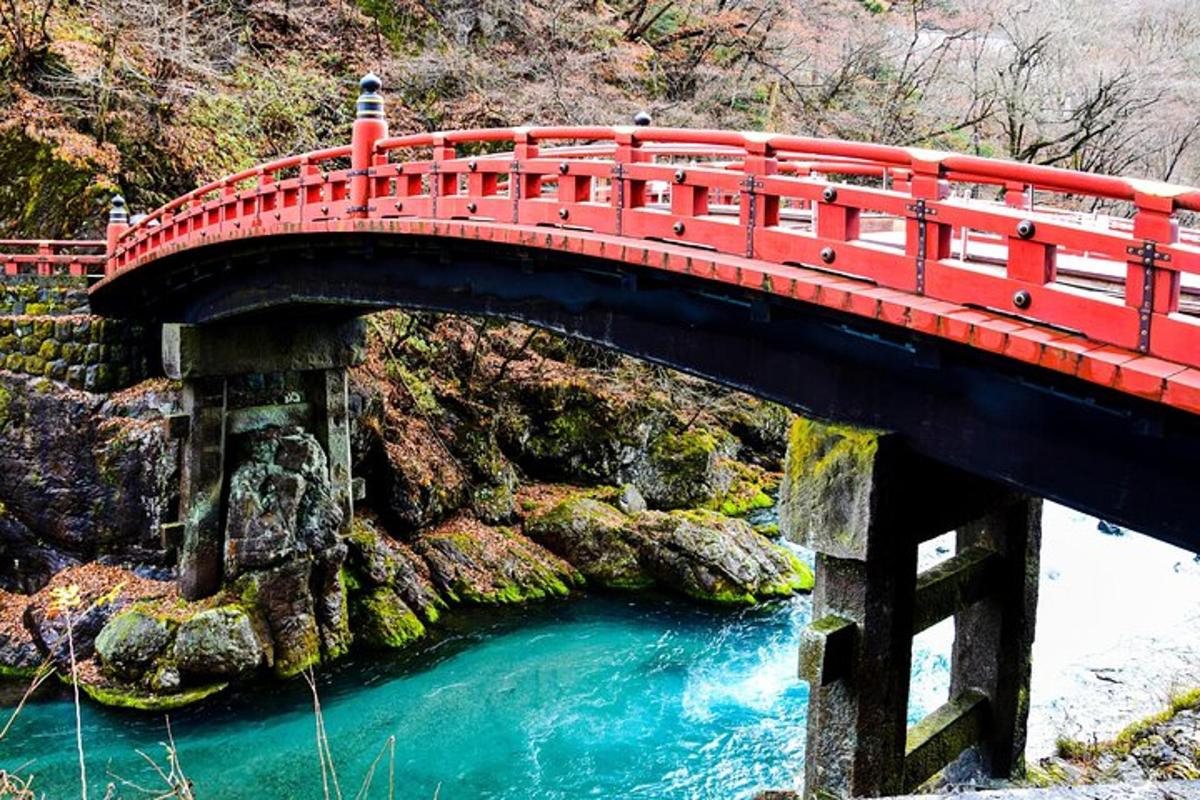 a red bridge over a river with blue water