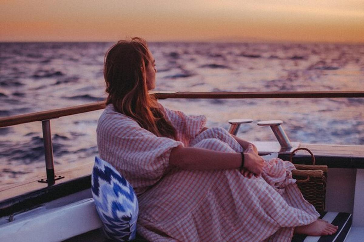 una donna seduta su una barca che guarda l'oceano
