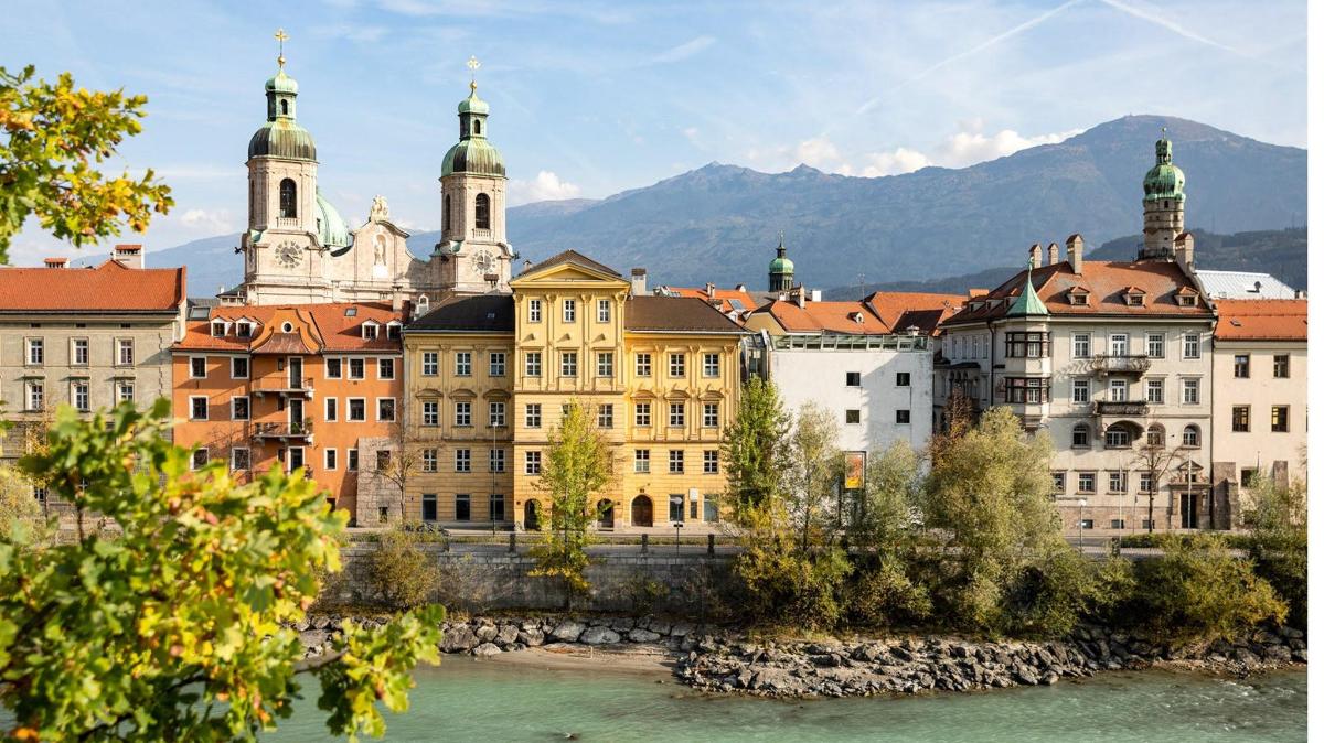 a group of buildings next to a river with mountains