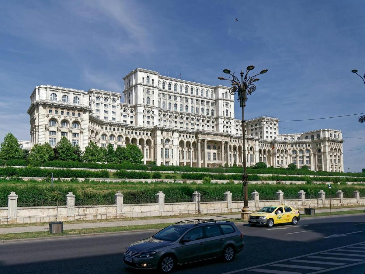 due auto che percorrono una strada di fronte a un grande edificio