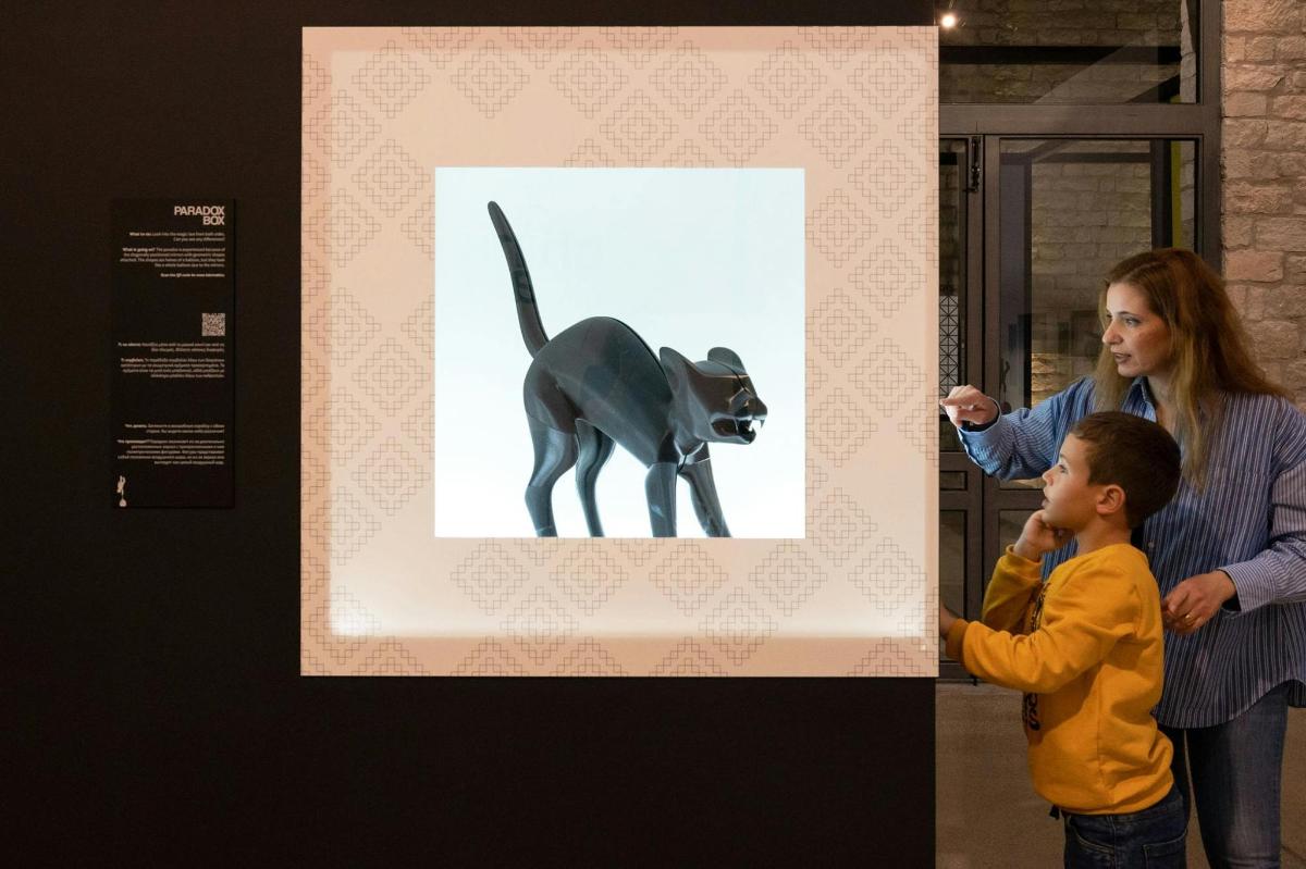 a woman and a child looking at a picture of a cat