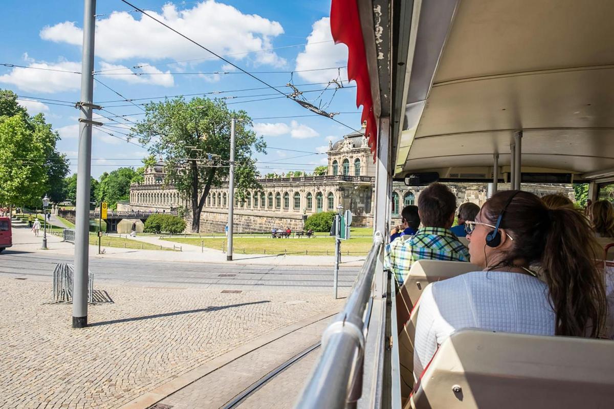 skupina lidí jedoucích v tramvaji před budovou